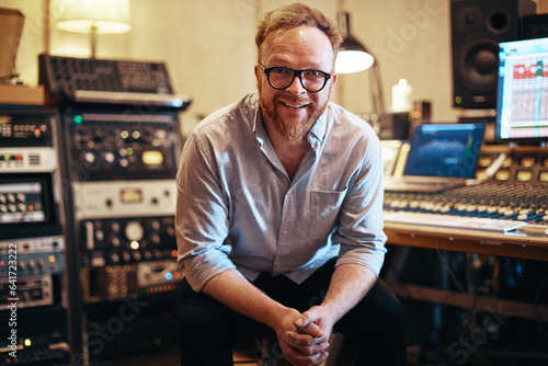 Music producer smiling while sitting in his recording studio photo