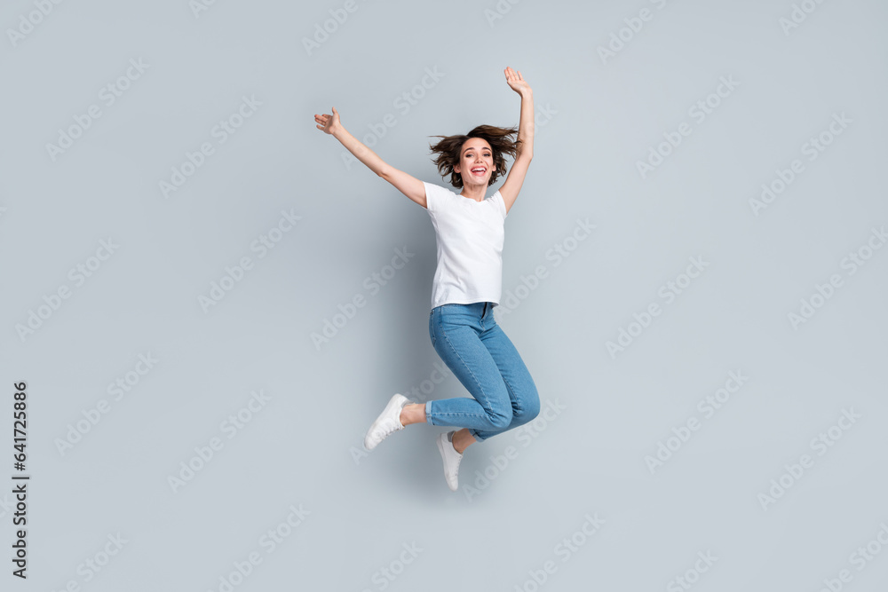 Full length photo of crazy cheerful person have good mood raise hands jumping flying isolated on grey color background