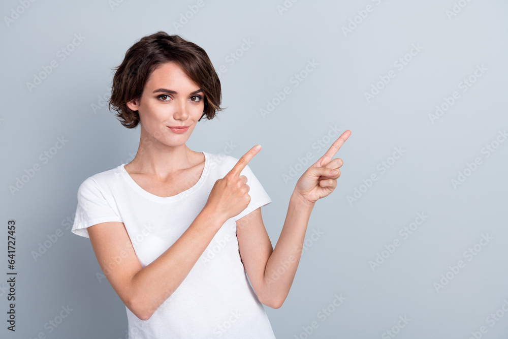 Photo of charming shiny lady wear white t-shirt showing two fingers empty space isolated grey color background Photo of charming shiny lady wear white t-shirt showing two fingers empty space isolated grey color background