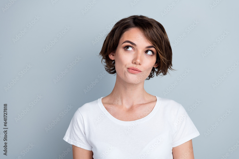 Photo of suspicious thoughtful lady wear white t-shirt looking empty space isolated grey color background Photo of suspicious thoughtful lady wear white t-shirt looking empty space isolated grey color background