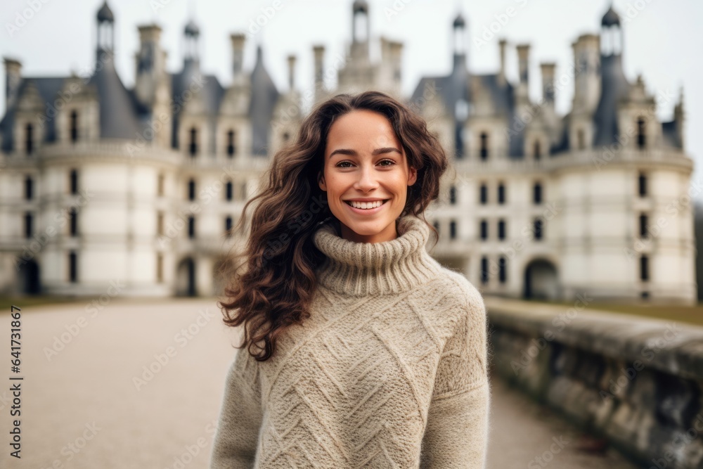 Lifestyle portrait photography of a grinning girl in her 20s smirking wearing a cozy sweater at the chateau de chambord in chambord france. With generative AI technology