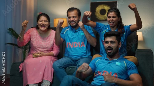 Group of excited encouraging family memebers shouting as India while watching Cricket sports match at home - concept of encouraging, emotional bonding and joyful reaction photo
