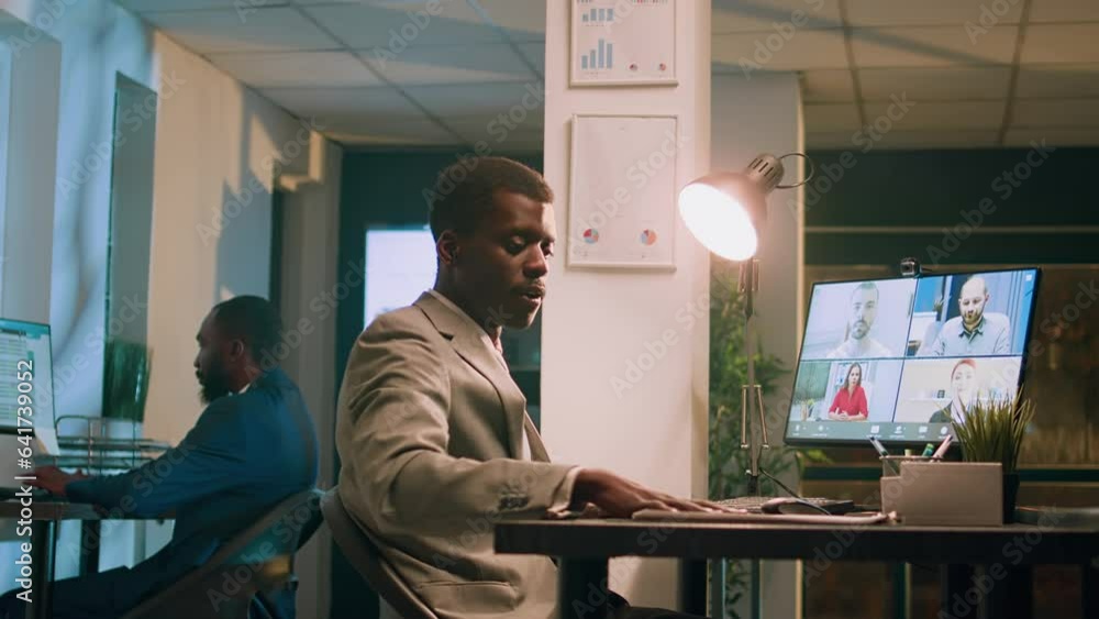 Seasoned company manager working overnight in office, holding team teleconference meeting with employees. Management executive chatting with staff members during online videocall