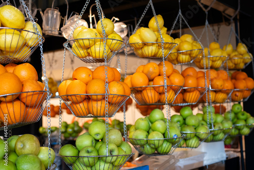 Various type of fresh fruits hang on steel basket in frui juice stall. Apple  Orange and Lemon on steel basket