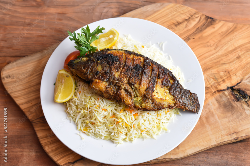 Shiri Fish fry with White Rice, tomato and lime served in dish isolated on wooden table top view middle eastern lunch food Shiri Fish fry with White Rice, tomato and lime served in dish isolated on wooden table top view middle eastern lunch food