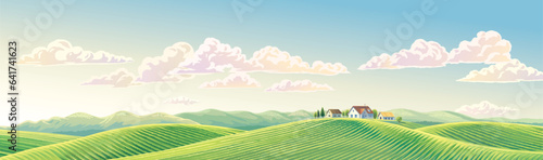 Summer rural landscape panoramic format, with hills and agriculture fields and village, on top of a hill.