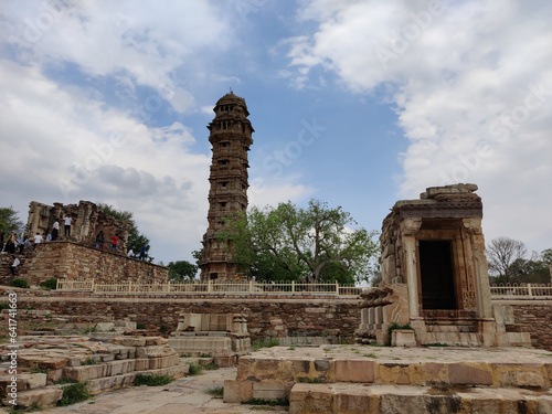 Picture of monument at Chittorgarh Fort with Vijay Stambha in background shot during daylight against blue sky and white clouds
 photo