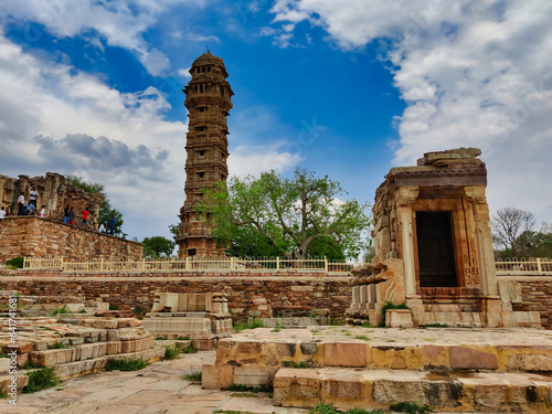 Picture of monument at Chittorgarh Fort with Vijay Stambha in background shot during daylight against blue sky and white clouds
 photo