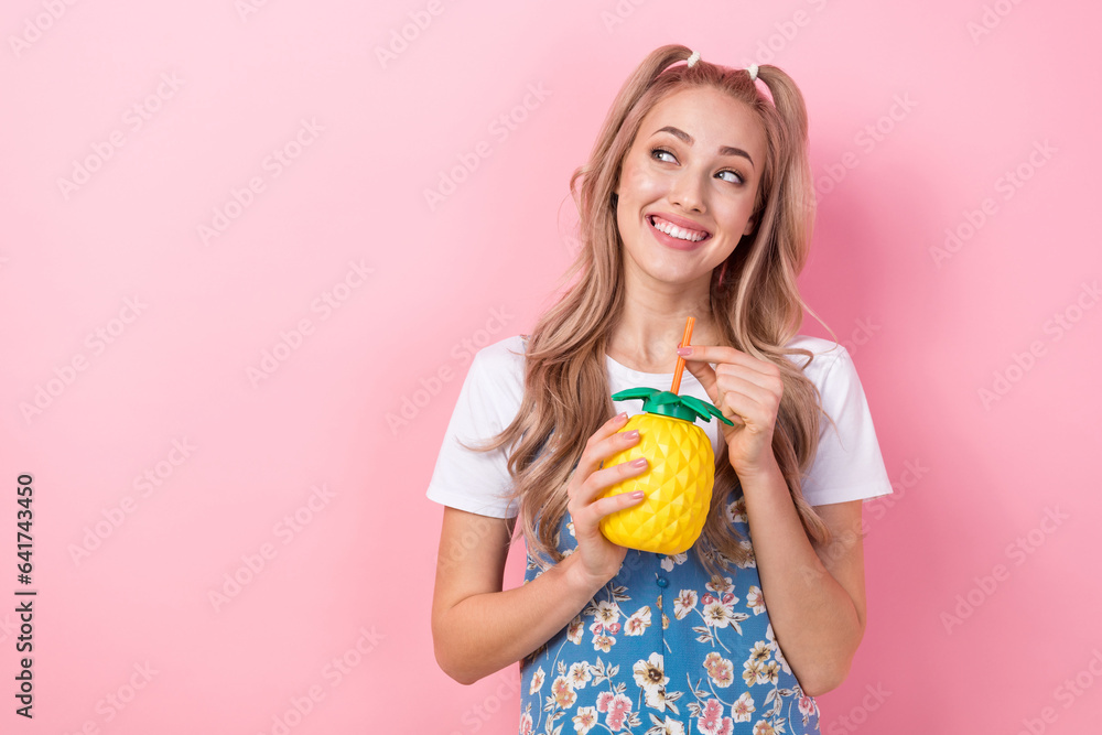 Photo of adorable cheerful person hold pineapple juice cup straw look empty space isolated on pink color background Photo of adorable cheerful person hold pineapple juice cup straw look empty space isolated on pink color background