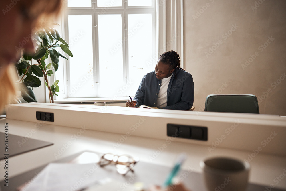 © Flamingo Images - African businessman writing at his office desk © Flamingo Images - African businessman writing at his office desk
