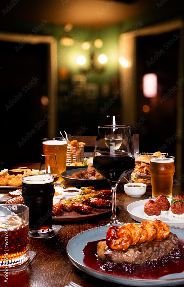 dinner banquet at a table set with dishes such as surf and turf starters beers wines drinks at an angle
