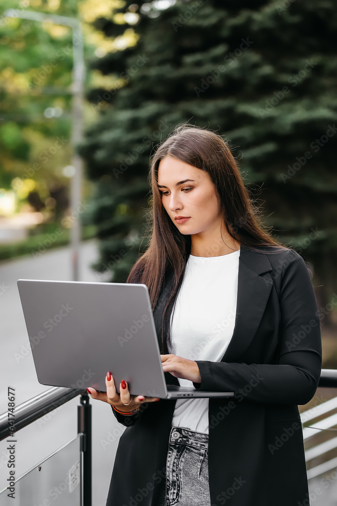 Happy young business woman typing on a laptop. A woman in a suit is satisfied with her work and a successful deal.
Happy young business woman typing on a laptop. A woman in a suit is satisfied with her work and a successful deal.