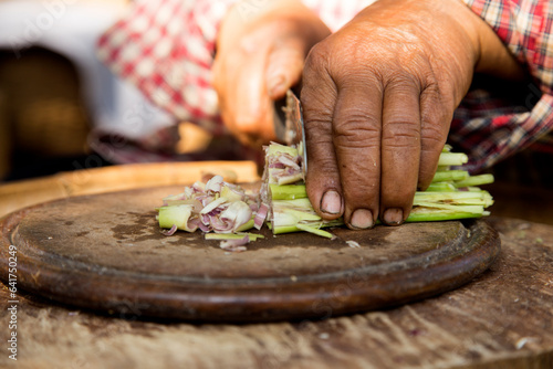 A woman cutting lemon grass on a wooden board in Chiang Mai, Thailand.