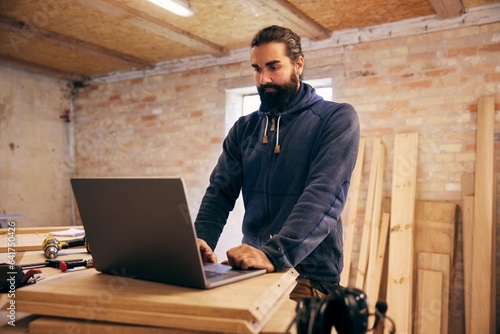 Woodworker using a laptop in his carpentry shop photo