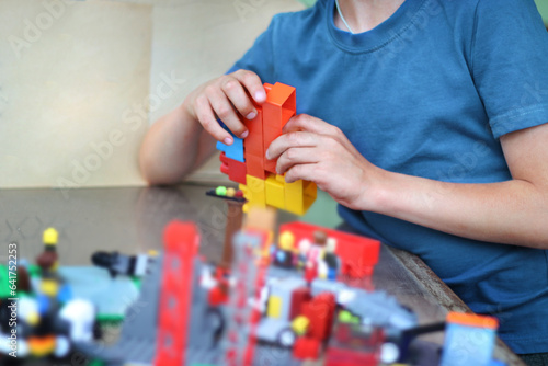Photos An unrecognizable boy assembles multi-colored constructor.
