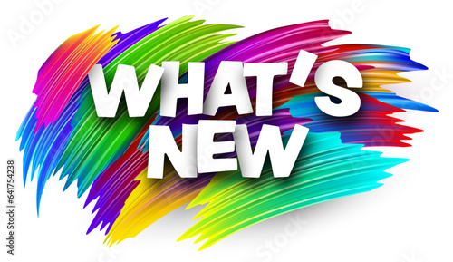 What's new paper word sign with colorful spectrum paint brush strokes over white.