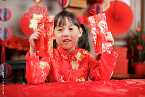 young girl with traditional dressing up celebrating Chinese new year against all kind of " FU" means" lucky" ornament and greeting card background