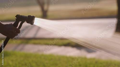 woman using a garden hose nozzle watering the lawn