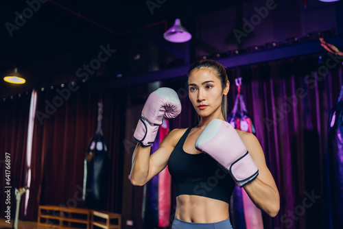 Female Boxer training in Boxing Club. Woman Boxing fighters training at gym. Strong muscular woman practicing box in pink boxing gloves in gym..