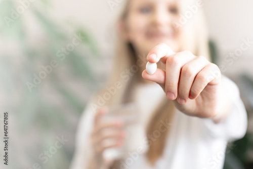 A girl holds a pill in her hand. Taking medications, vitamins.