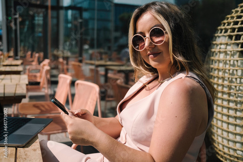 Tech Time in Style with Model Engaging with Phone Over Coffee in the City photo