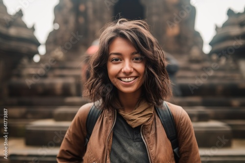 Close-up portrait photography of a happy girl in her 30s wearing a classic leather jacket at the borobudur temple in magelang indonesia. With generative AI technology