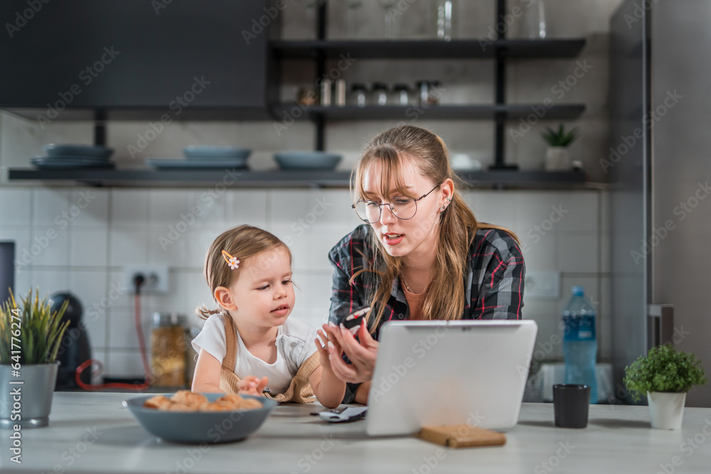 One young woman playing with toddler girl in the kitchen with finger puppets, babysitting at home concept One young woman playing with toddler girl in the kitchen with finger puppets, babysitting at home concept