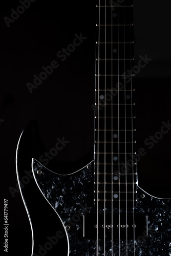 close up look of a black electric guitar isolated on black background. Vertical image