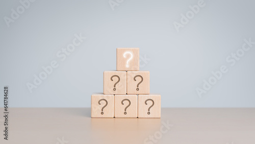 Stacked wooden cube blocks with question mark icons. Brainstorming, collaboration concept. Alternative thinking, ideas, confusion, Frequently Asked Questions, FAQ, questions, and Business solutions.