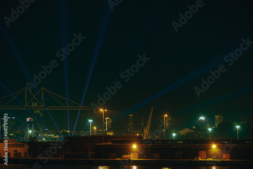 Night illumination at night in cargo port against background of urban landscape