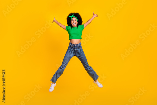 Full body portrait of active overjoyed person jumping raise hands make star figure isolated on yellow color background