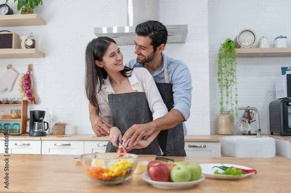 Happy couple preparing food at home, young couple cutting vegetables together at kitchen counter