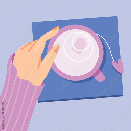 Hand holding a cup of tea on a napkin. View from the top of the table. 