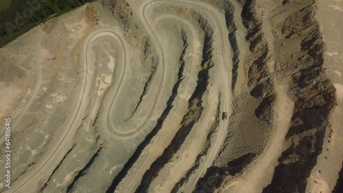 Epic drone shot of a dumper truck driving through a quarry construction site in the middle of the sunny day.