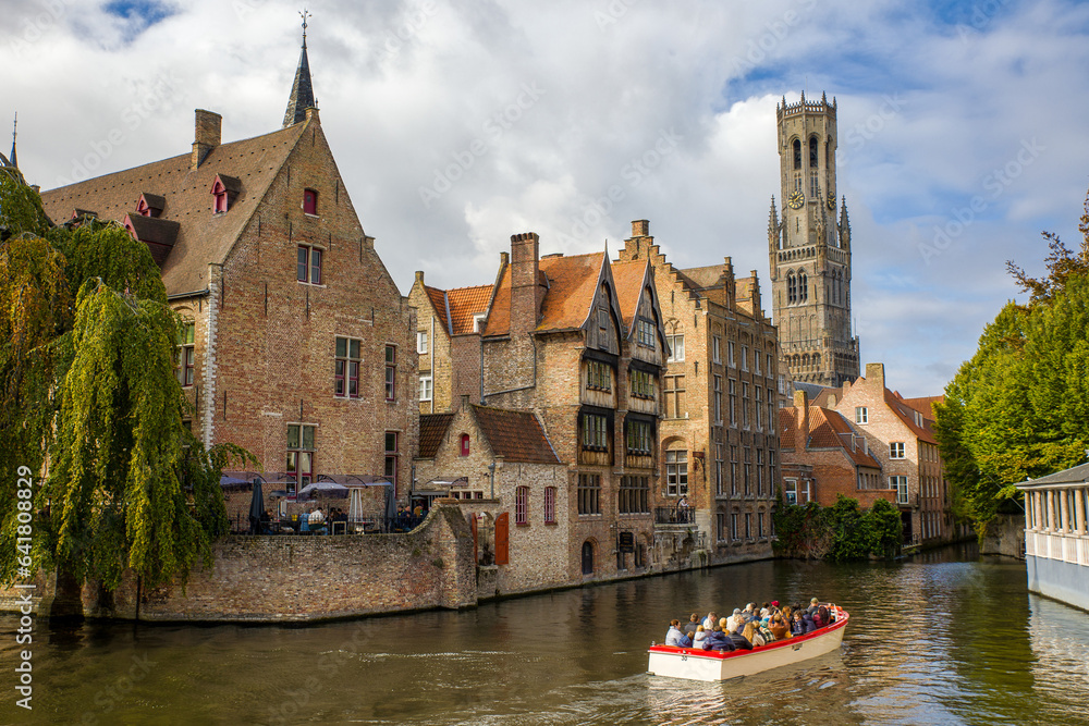 Obraz premium the Rozenhoedkaai canal in bruges with the famous belfry tower in the background and an excursion boat