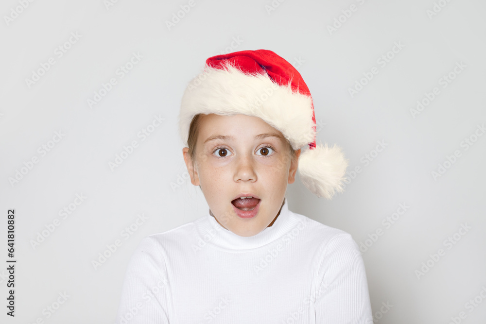 Surprised kid in Santa hat with opened mouth, Christmas portrait Surprised kid in Santa hat with opened mouth, Christmas portrait