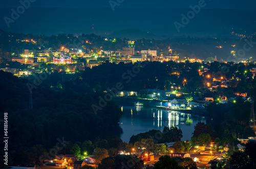 Cityscape of the city of Morgantown in West Virginia at night with lights and reflection in the river. The university campus is in the distance