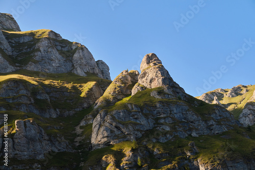 Shot capturing the beautiful mountain terrain in Bucegi National Park at sunset. Mountain landscape with green meadow and sharp rocks.