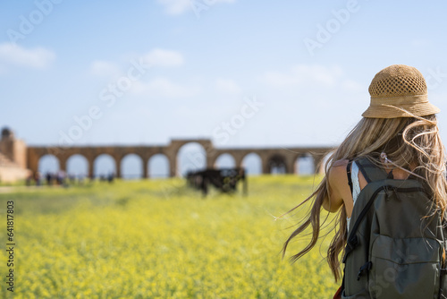 Canvas Print Rear view of tourist blonde woman with hat and long hair in Ancient Jerash ruins