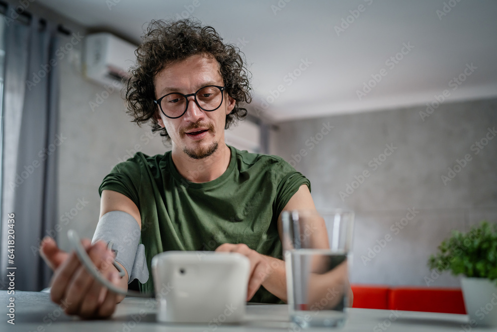 one adult caucasian man measure check blood pressure at home alone one adult caucasian man measure check blood pressure at home alone
