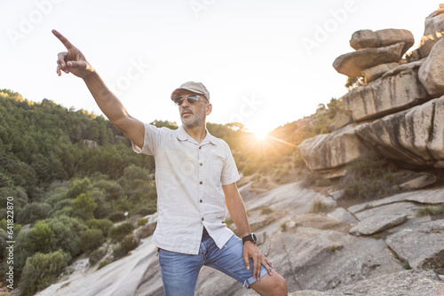 Man in sunglasses on rough surface pointing away photo