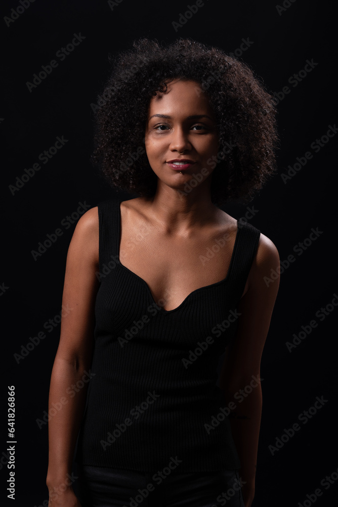 Smiling ethnic woman looking at camera in dark studio Smiling ethnic woman looking at camera in dark studio