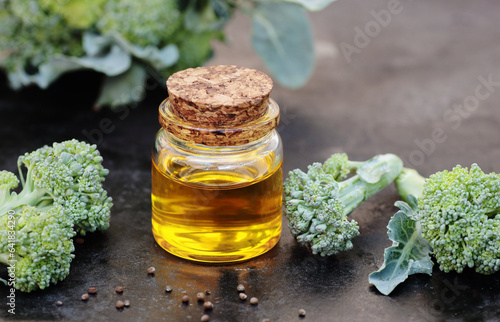 Broccoli seed oil with fresh vegetable on black background, closeup, natural cosmetics ingredient for homemade cosmetic beauty products, skincare, spa, natural hair care concepts photo