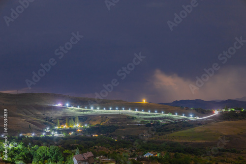 Long distance shot of a village and a brightly lit road in the highlands in the evening, Yerevan-Garni highway