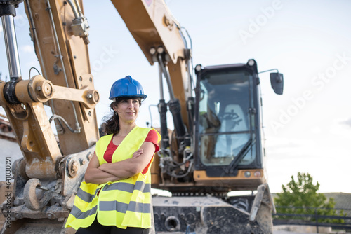 Female construction worker near to backhoe