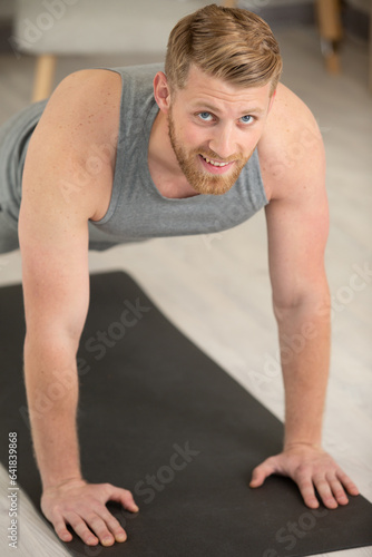 smiling man doing push-ups in the gym or at home © auremar