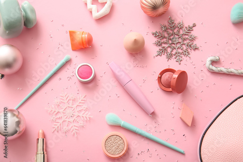 Makeup products and Christmas decorations on pink background