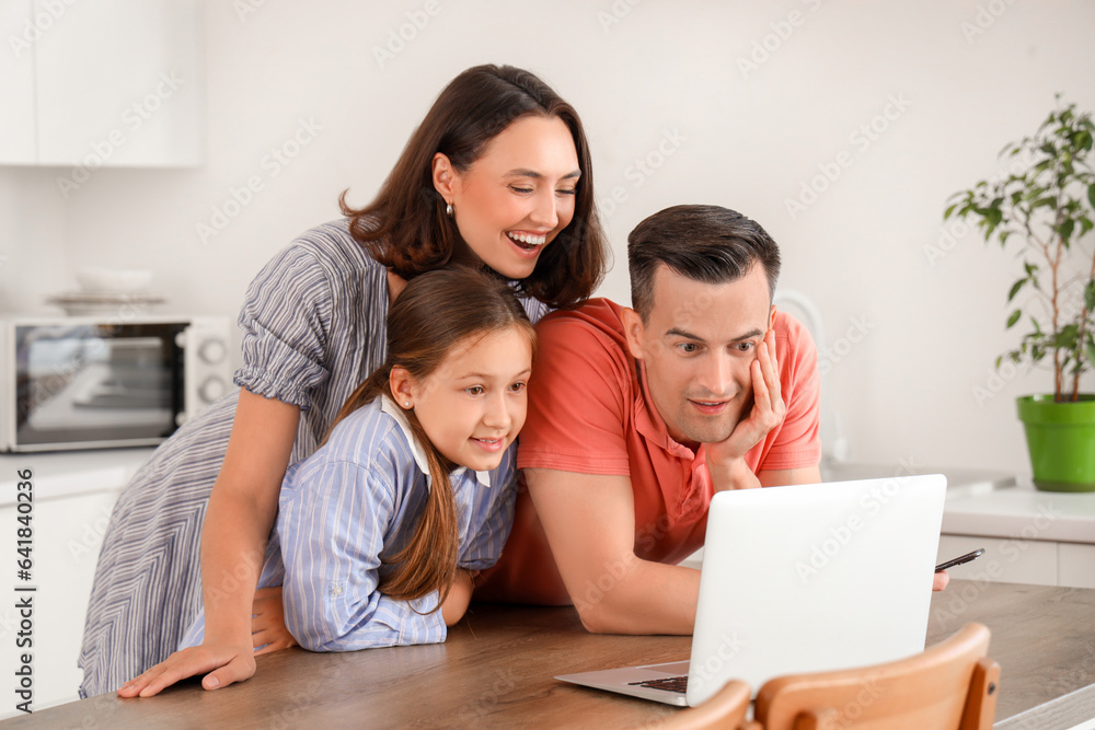 Happy family with laptop resting at table in kitchen Happy family with laptop resting at table in kitchen