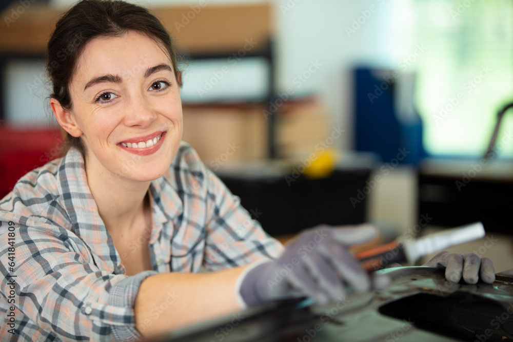 Fototapeta premium woman builder working at workshop with gloves