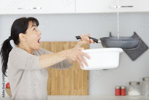 frustrated woman collecting water from ceiling